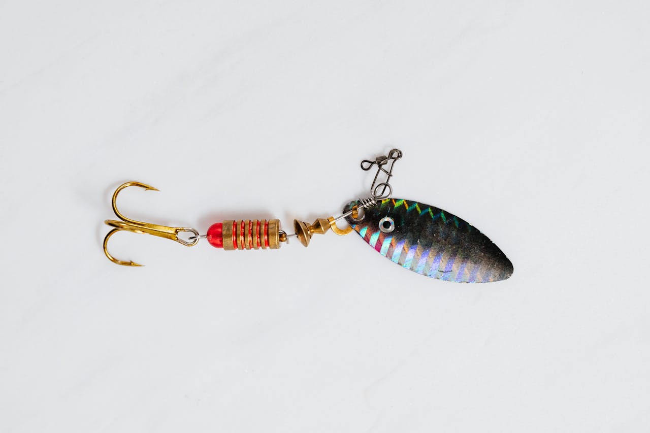 A close-up shot of a colorful metallic fishing lure with hook on a white surface.