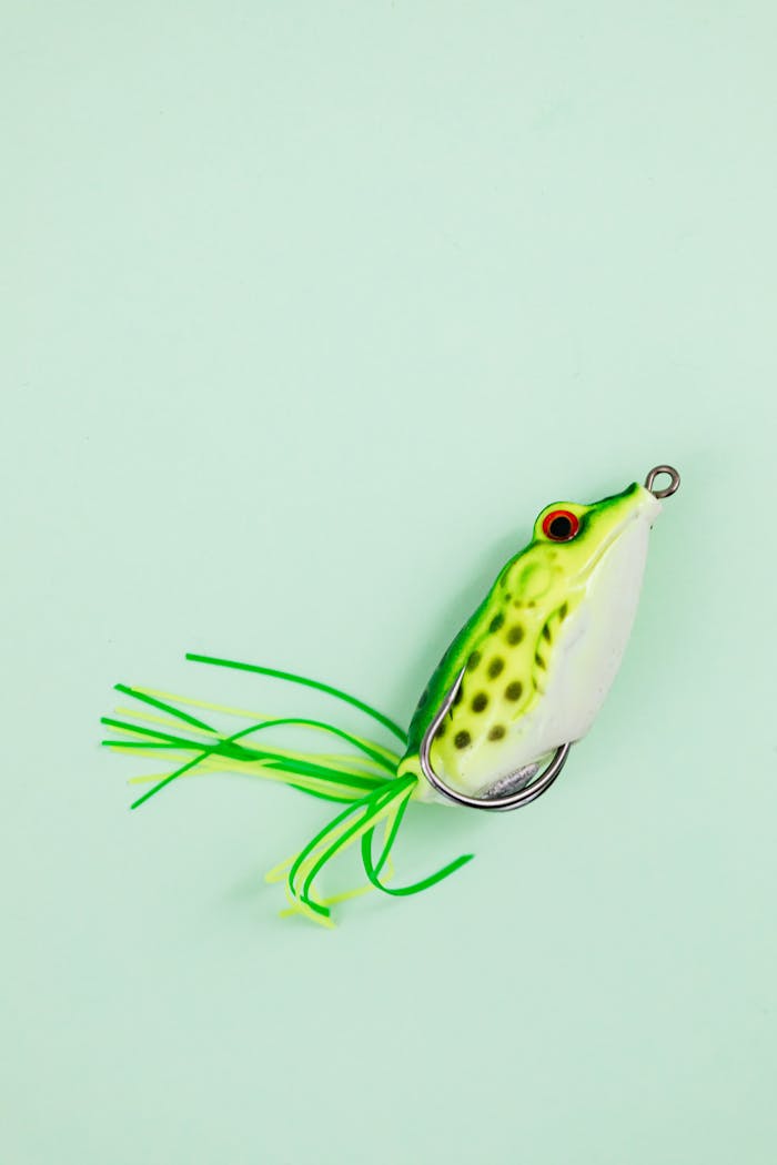 A close-up of a frog-shaped fishing lure with vivid colors on a green background.